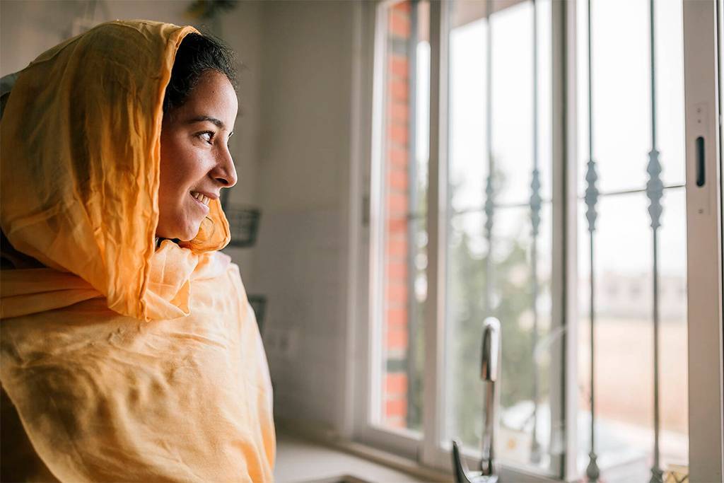 Junge Frau schaut aus dem Fenster und steht in der Küche
Lizenzfreies Stockfoto