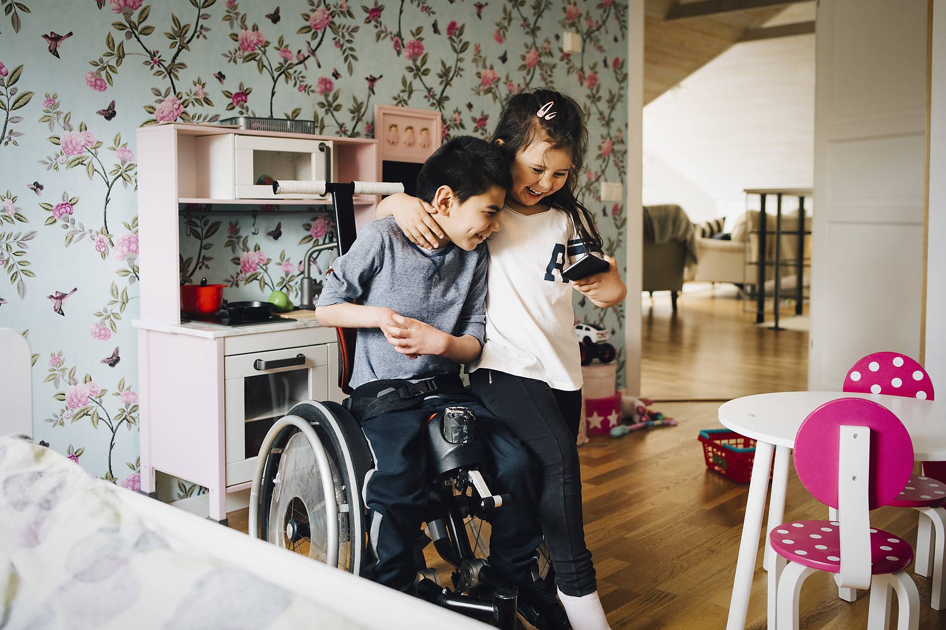 Stock photo, royalt-free, Cheerful sister watching video with autistic brother on mobile phone at home, Diversity