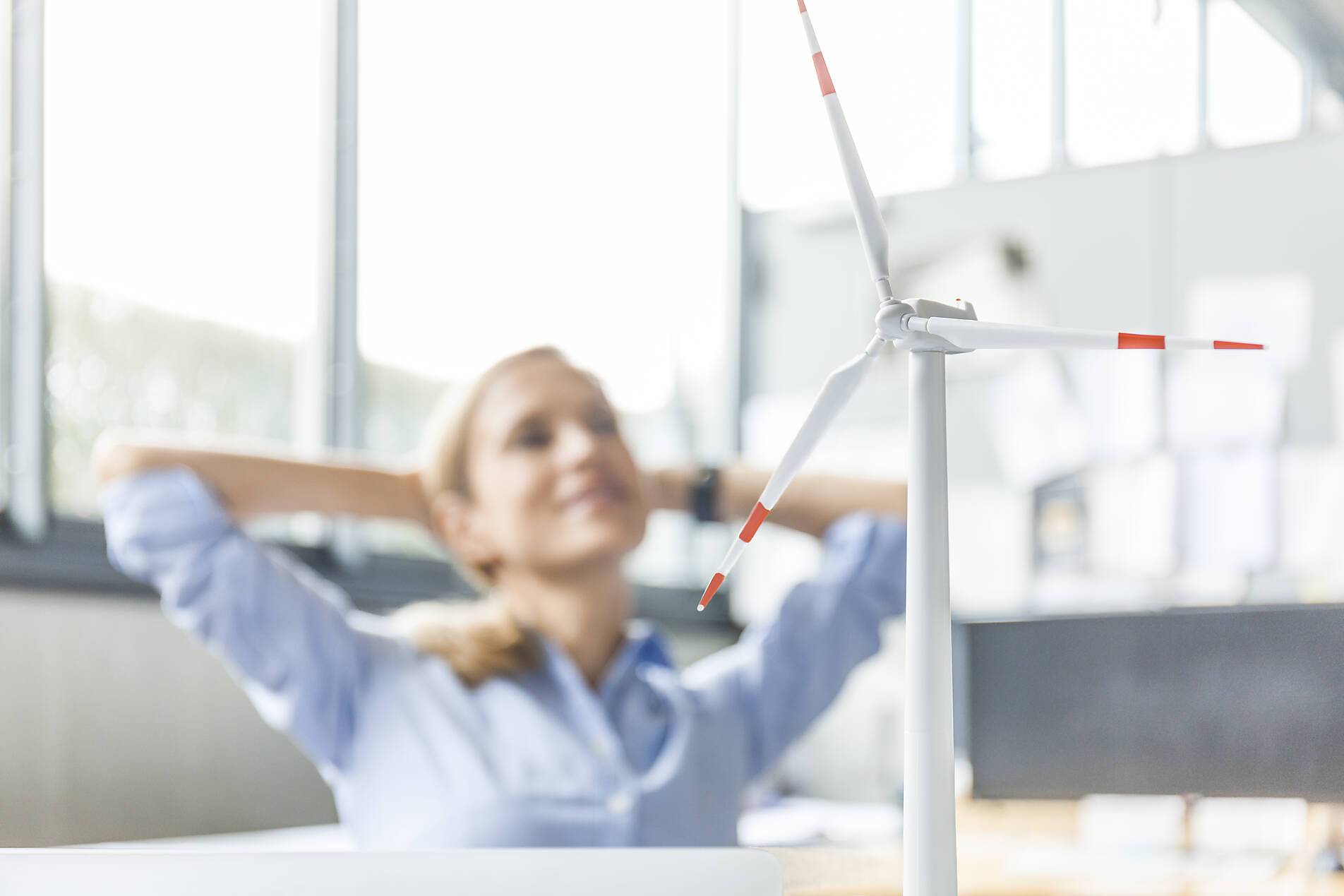 Stock image, royalty-free, Wind turbine model and woman in background in office