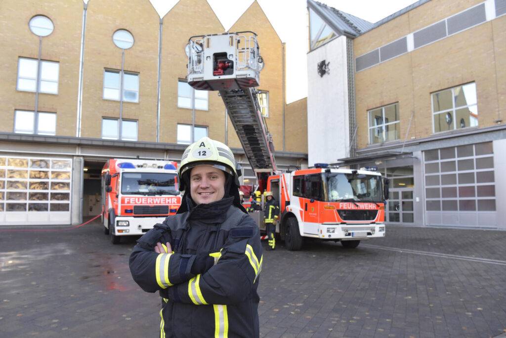 stock image,royalty-free, Portrait of smiling firefighter in front of fire engine with colleagues in background