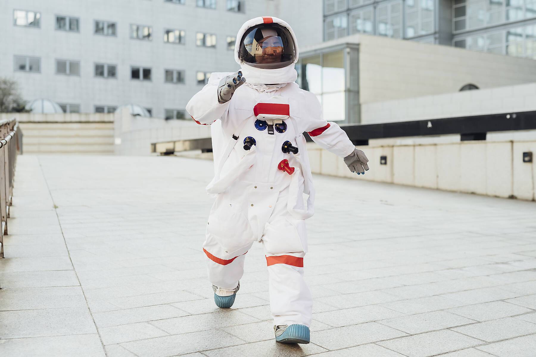 stock image, royalty-free, Young female astronaut in space suit walking on boardwalk near building in city - Italy, Lombardy, Milan - freedom, ambition, new planets, exploration, surreal