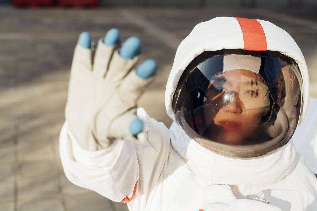 Junge weibliche Astronautin im Raumanzug schirmt Augen durch Sonnenlicht ab