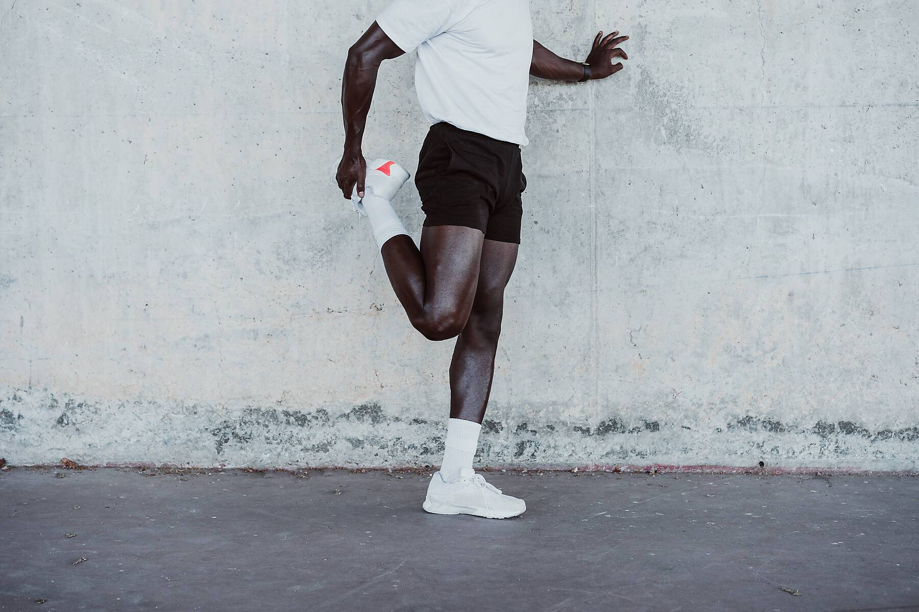 stock image, royalty-free, Young athlete doing stretching exercise while standing by wall