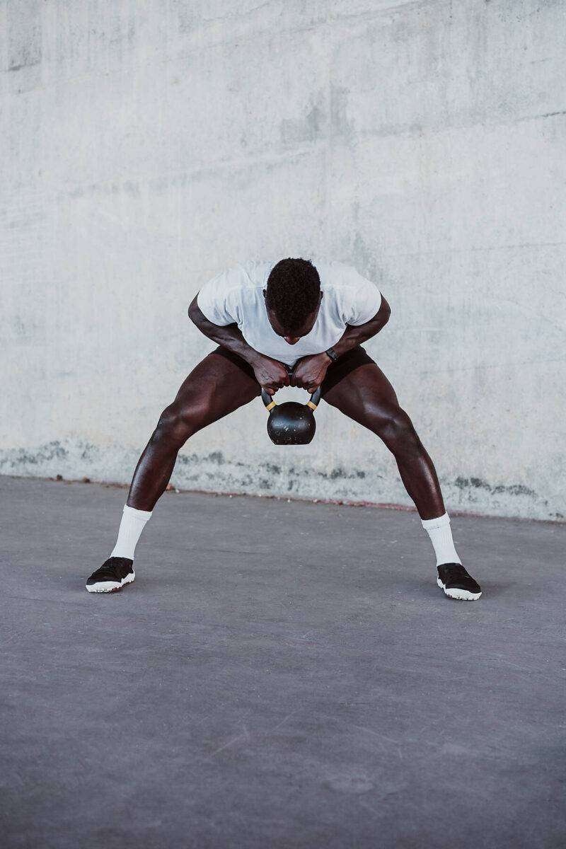 royalty-free, stock images, Male athlete lifting kettle bell while standing against white wall