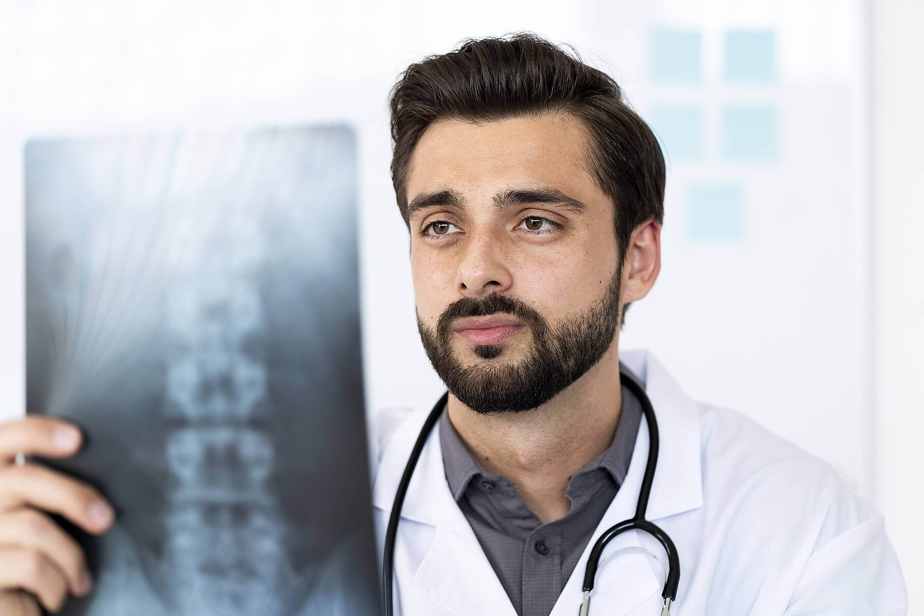Handsome male healthcare worker analyzing X-ray in hospital