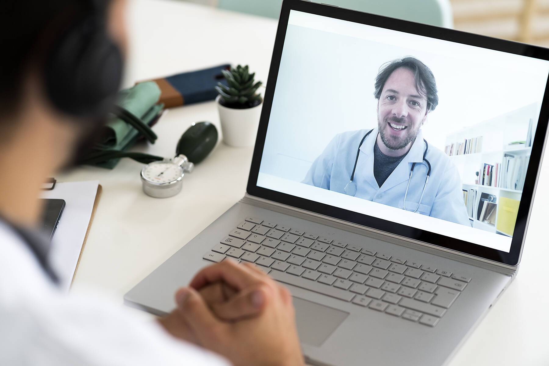 Male healthcare worker discussing with doctor through video conference