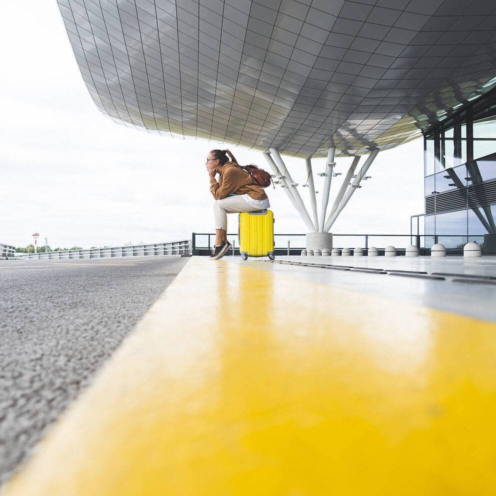 stock image, royalty-free, Young woman sitting on luggage while waiting at airport