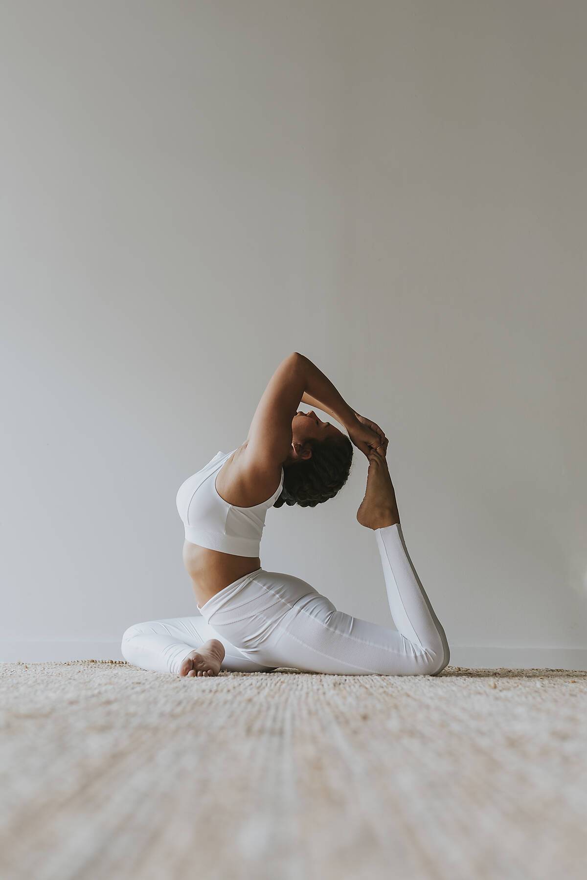 Flexible yogi practicing yoga by wall at studio