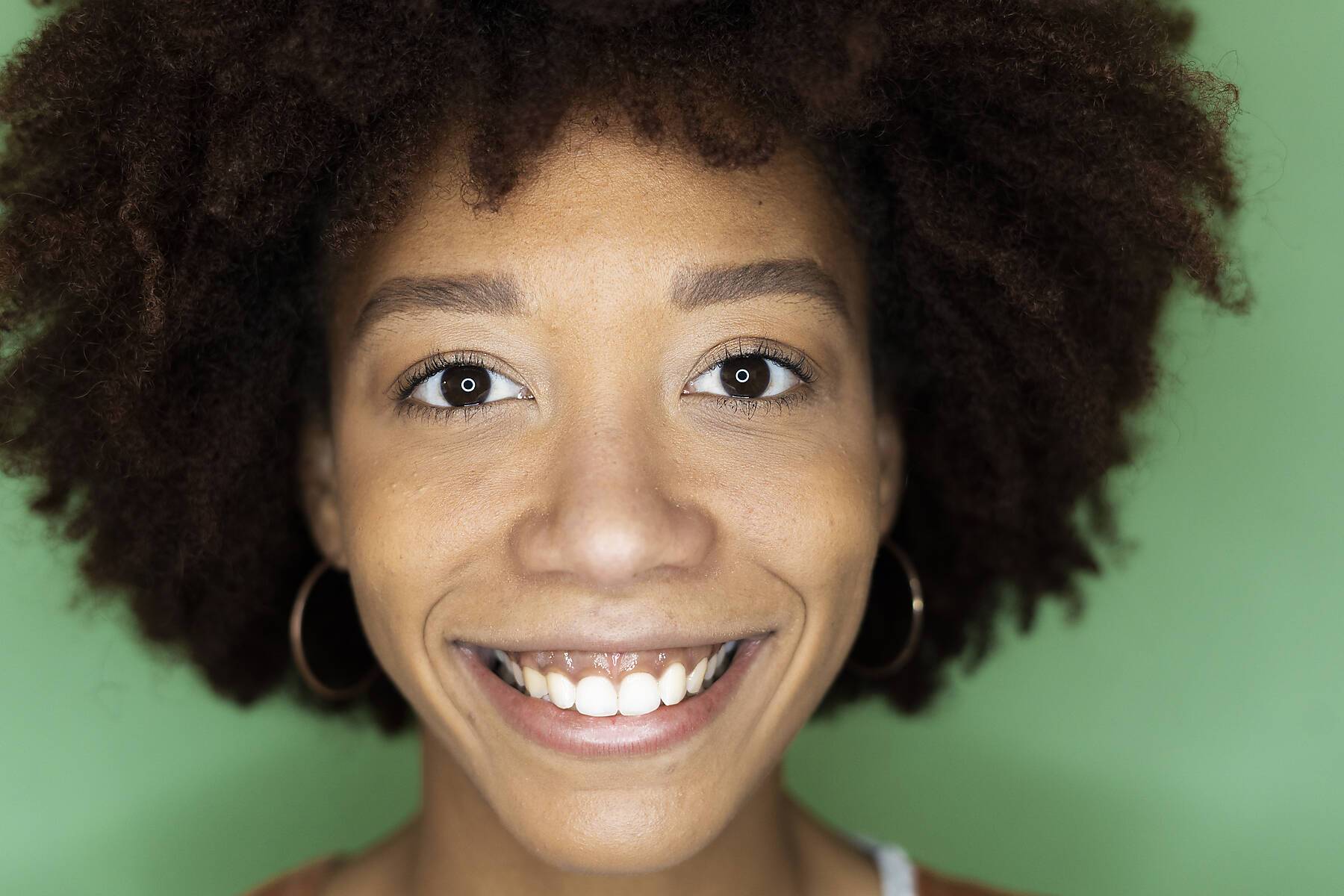 Happy Afro woman against green wall in new loft apartment