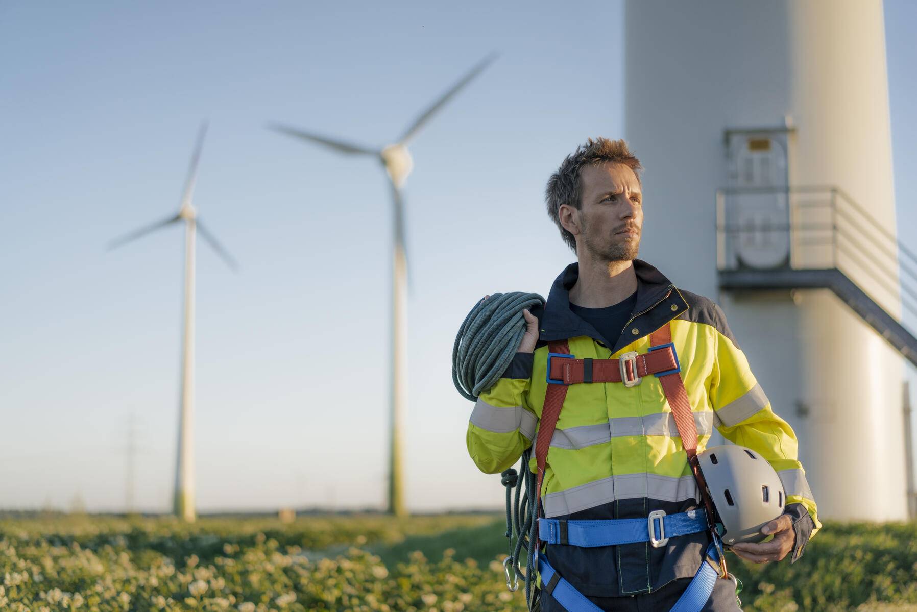 Technician standing at a wind farm with climbing equipment