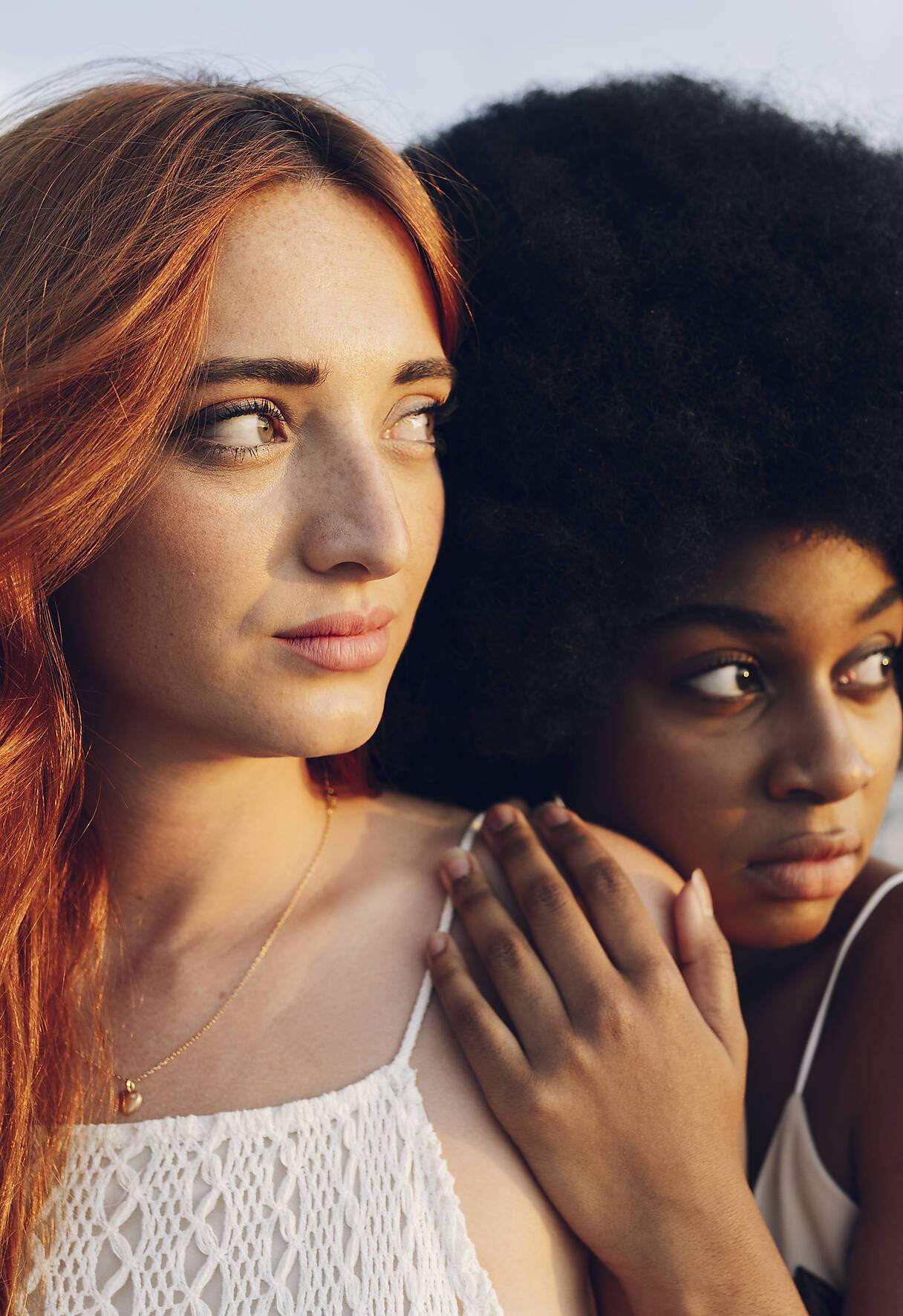 Afro woman looking away while leaning on girlfriend