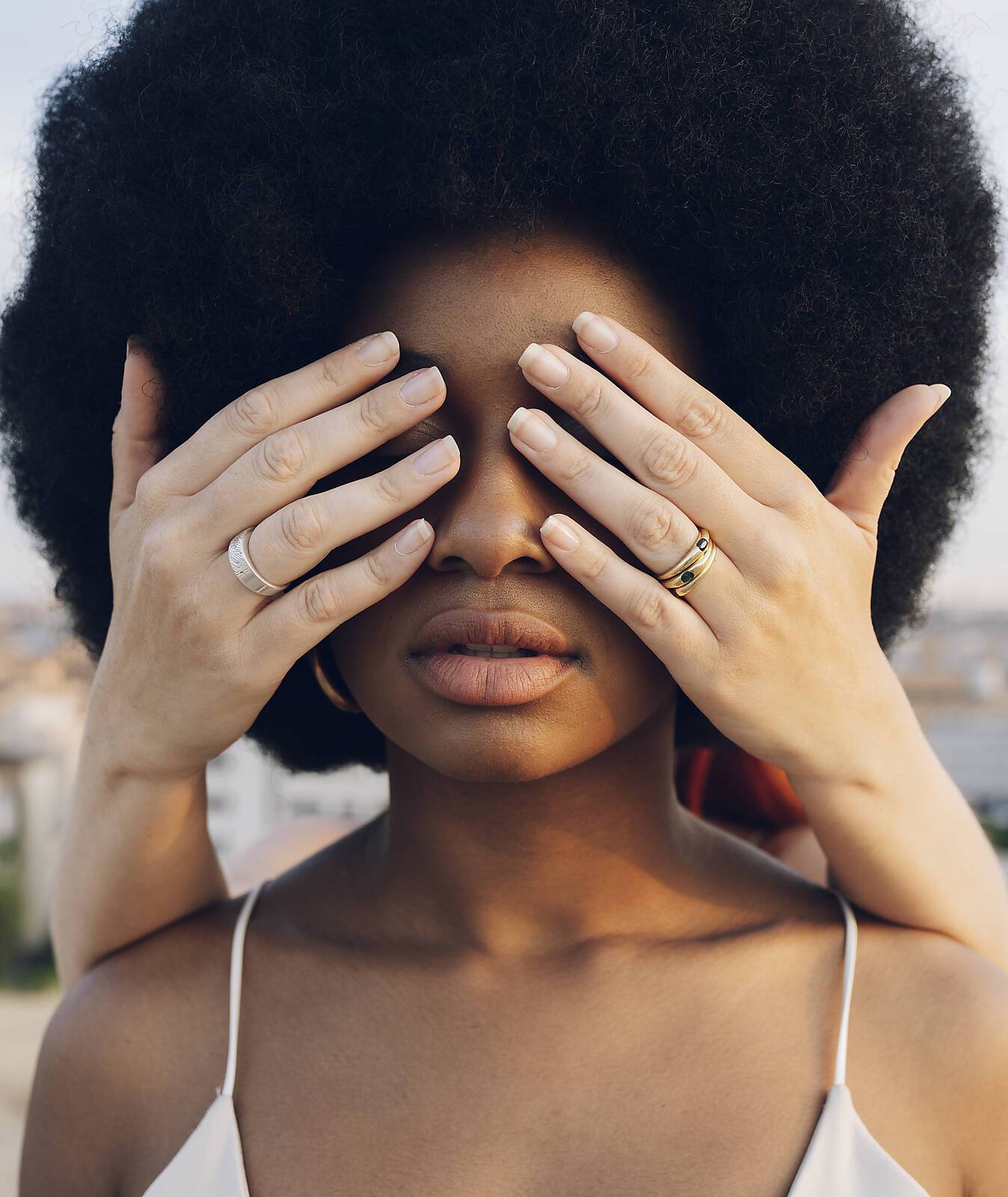 Young woman covering Afro girlfriend's eyes