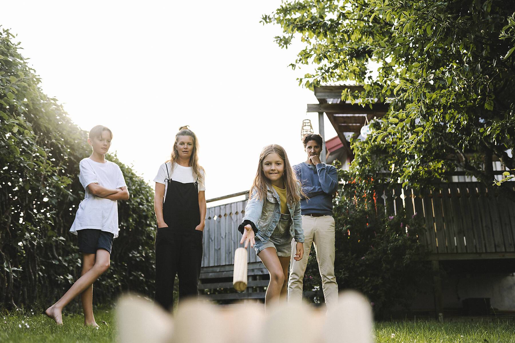 Stock Image, royalty-free, Girl playing molkky with family in back yard