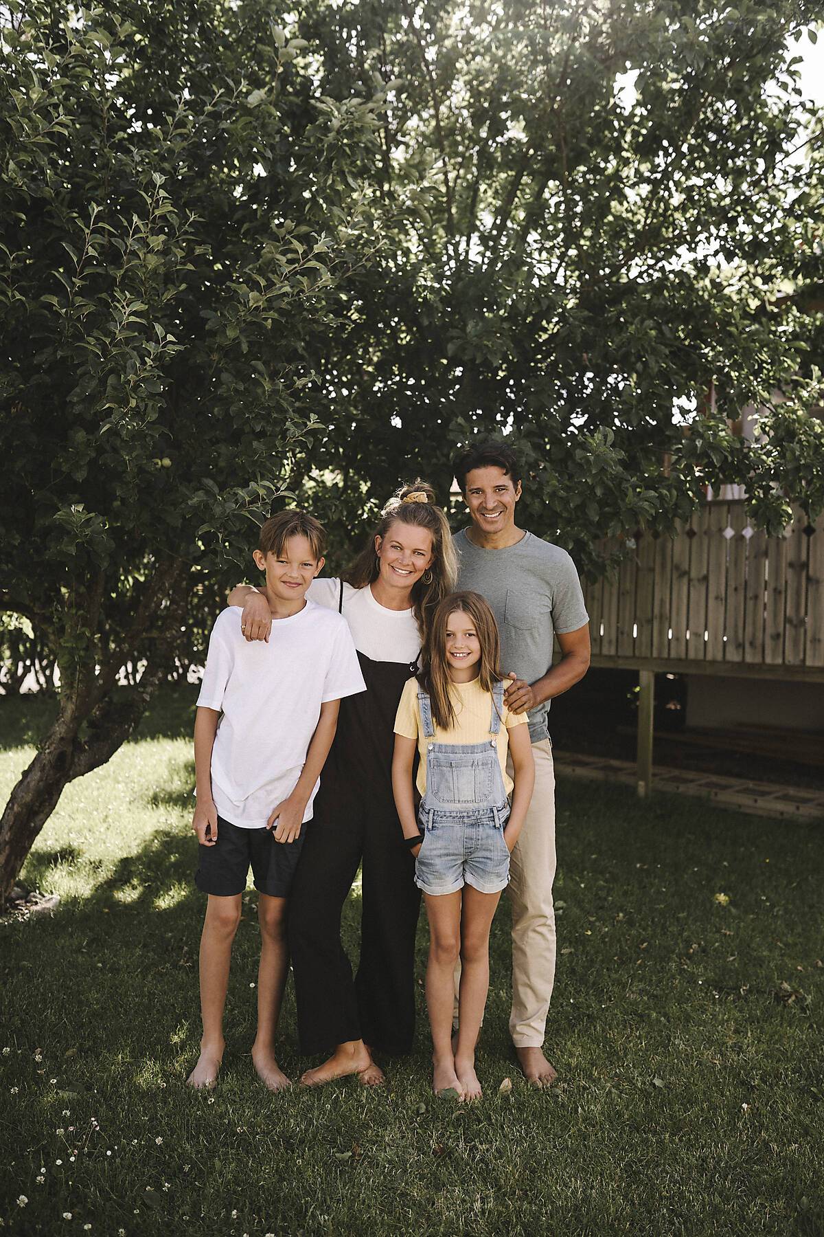 Stock Image, royalty-free, Happy family standing against tree in back yard
