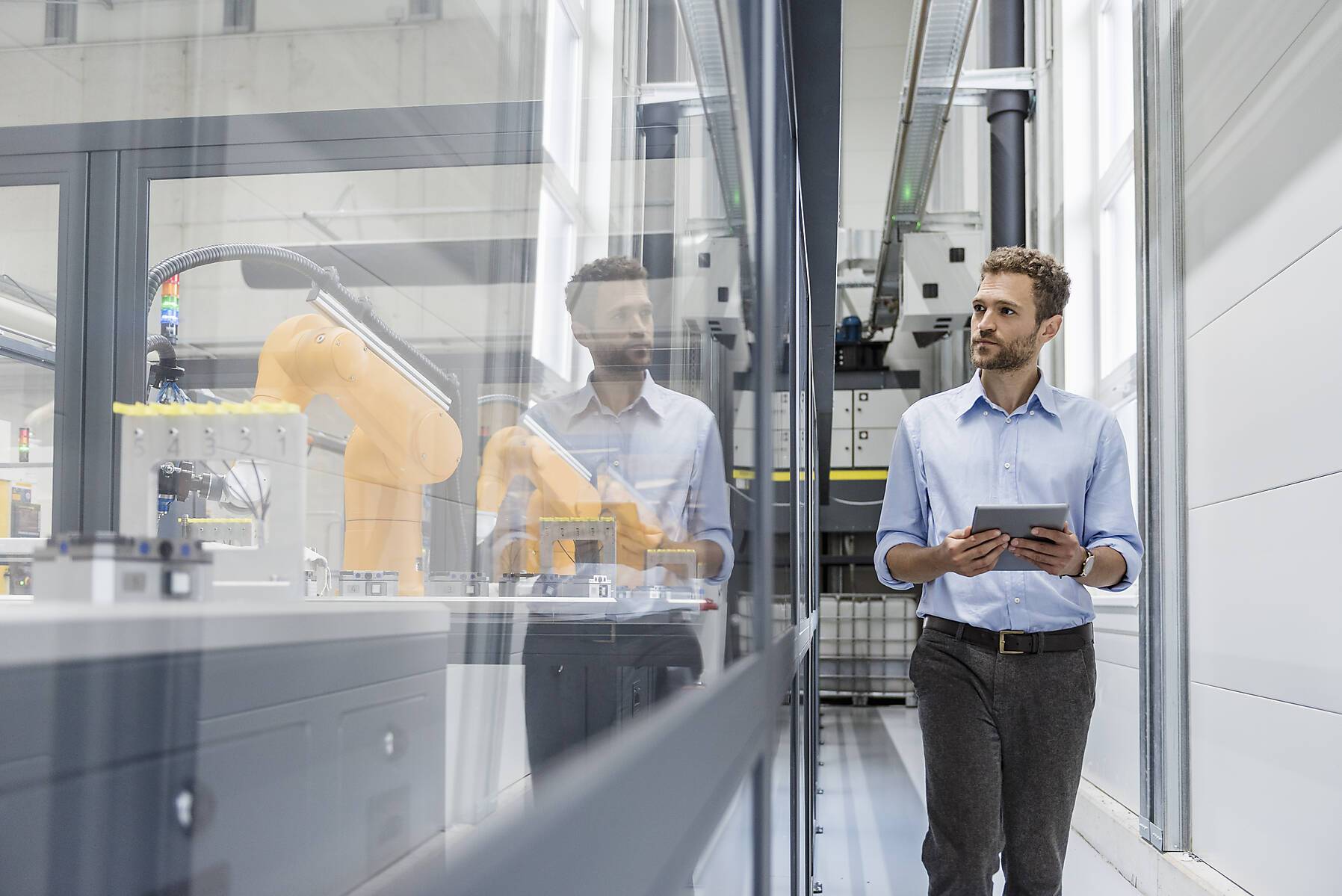 Stock image, roylty-free, Businessman checking robots with digital tablet in high tech company