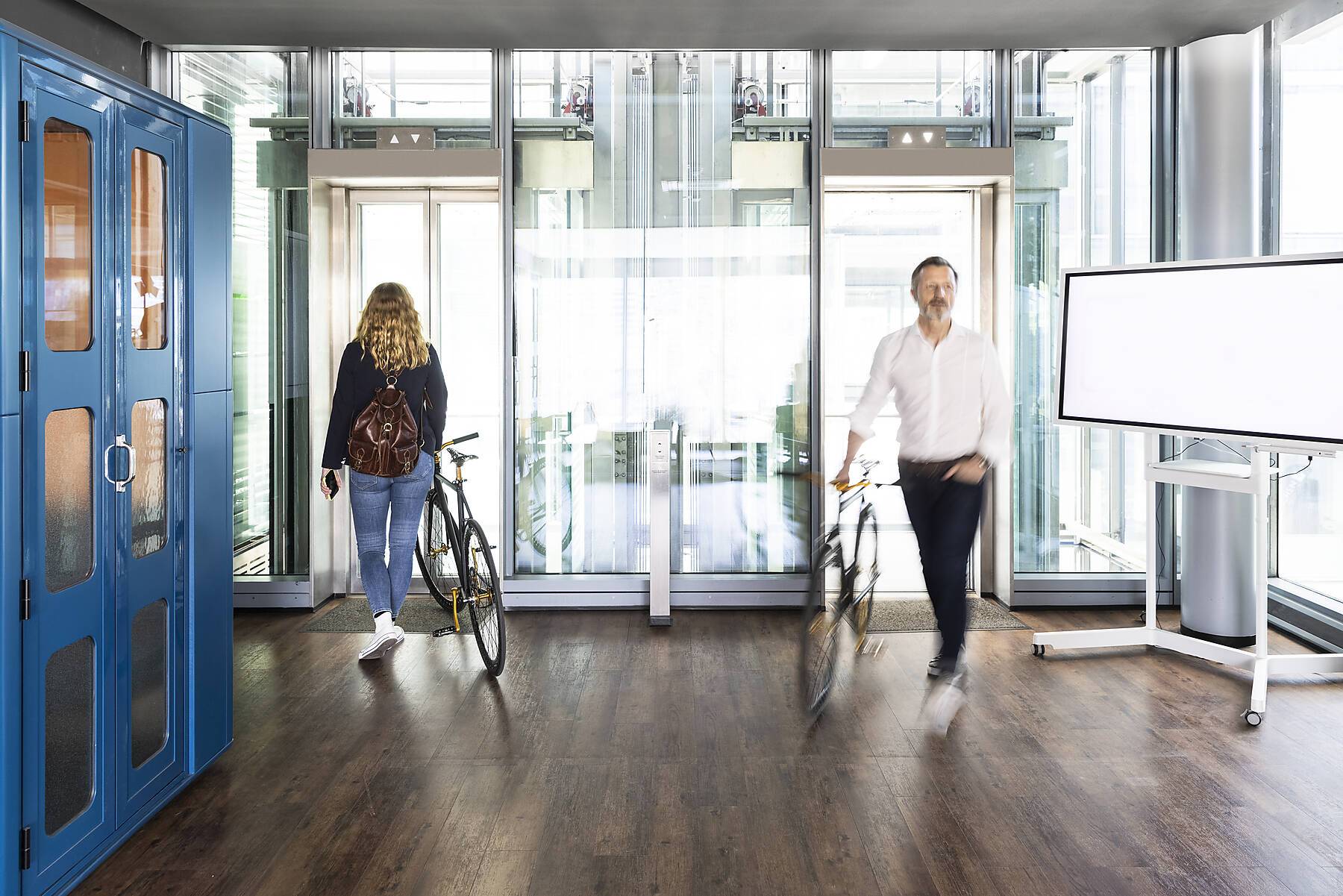 stock image, royalty-free, Businessman entering while female colleague leaving with bicycle at office