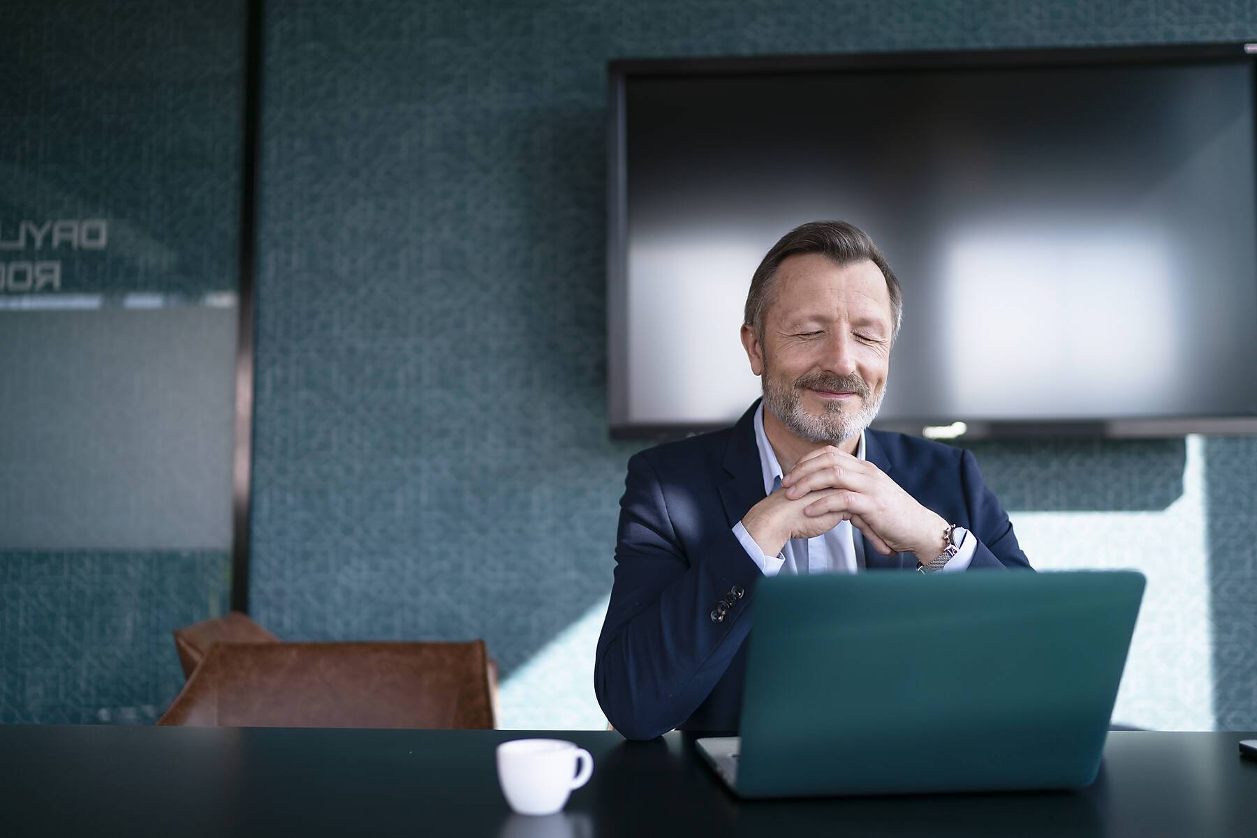 stock image, royalty-free, Smiling businessman with hands clasped looking at laptop in office