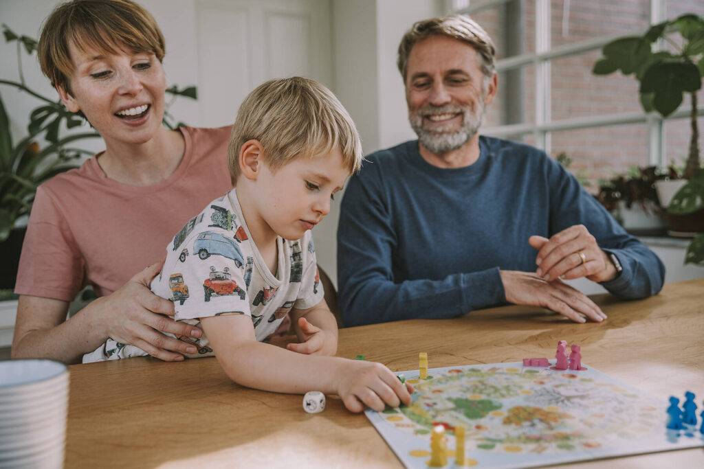 stockfoto, lizenzfrei, Eltern spielen Brettspiel mit dem Sohn zu Hause