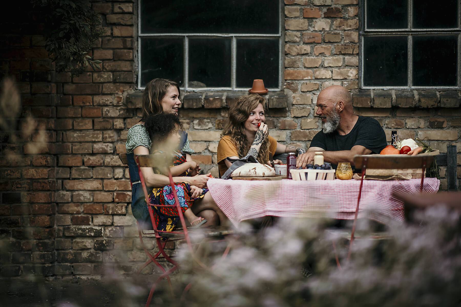 Lizenzfreies Stockfoto, Lächelnde Freunde unterhalten sich beim Gemüseessen im Garten