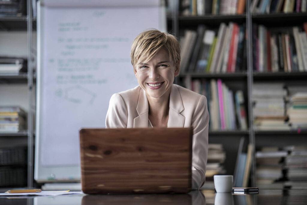 Stockfoto, lizenzfrei, Porträt einer lächelnden Geschäftsfrau mit Laptop im modernen Konferenzraum