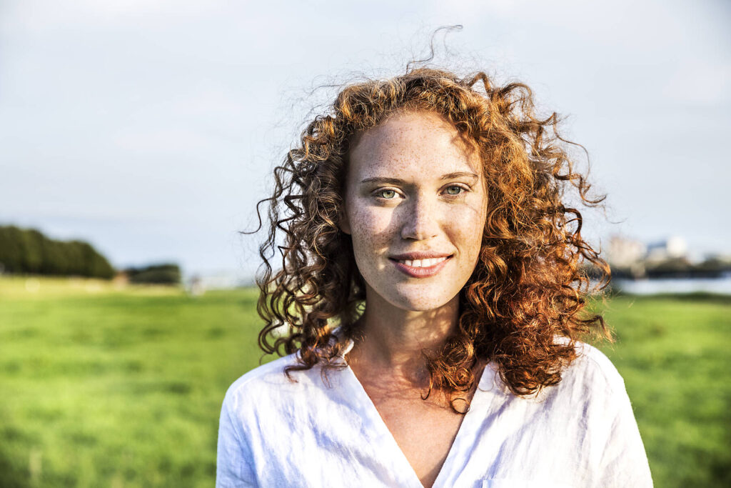 Stockfoto, lizenzfrei, Bildnis einer sommersprossigen jungen Frau mit lockigem roten Haar