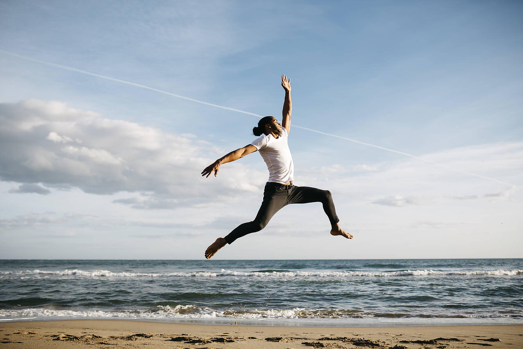 stock image, royalty-free, Spain, Tarragona, Calafell. Latin man sitting on the promenade, a sunny day.. Latin man jumping happy on the beach.