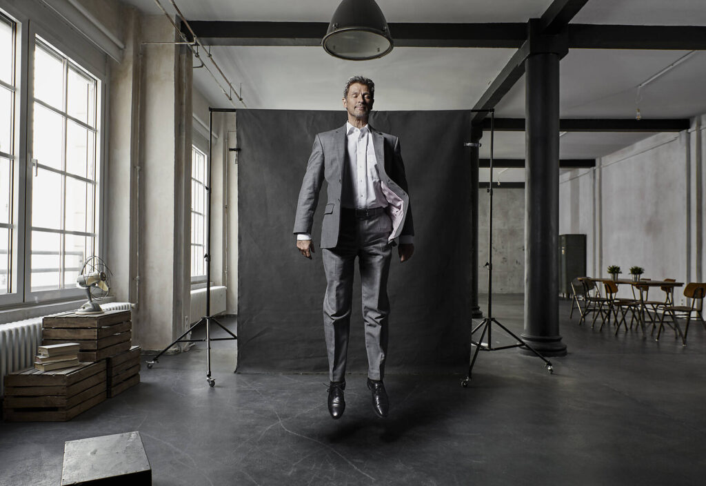 stockfoto, lizenzfrei, Ein reifer Geschäftsmann schwebt vor schwarzem Hintergrund im Loft