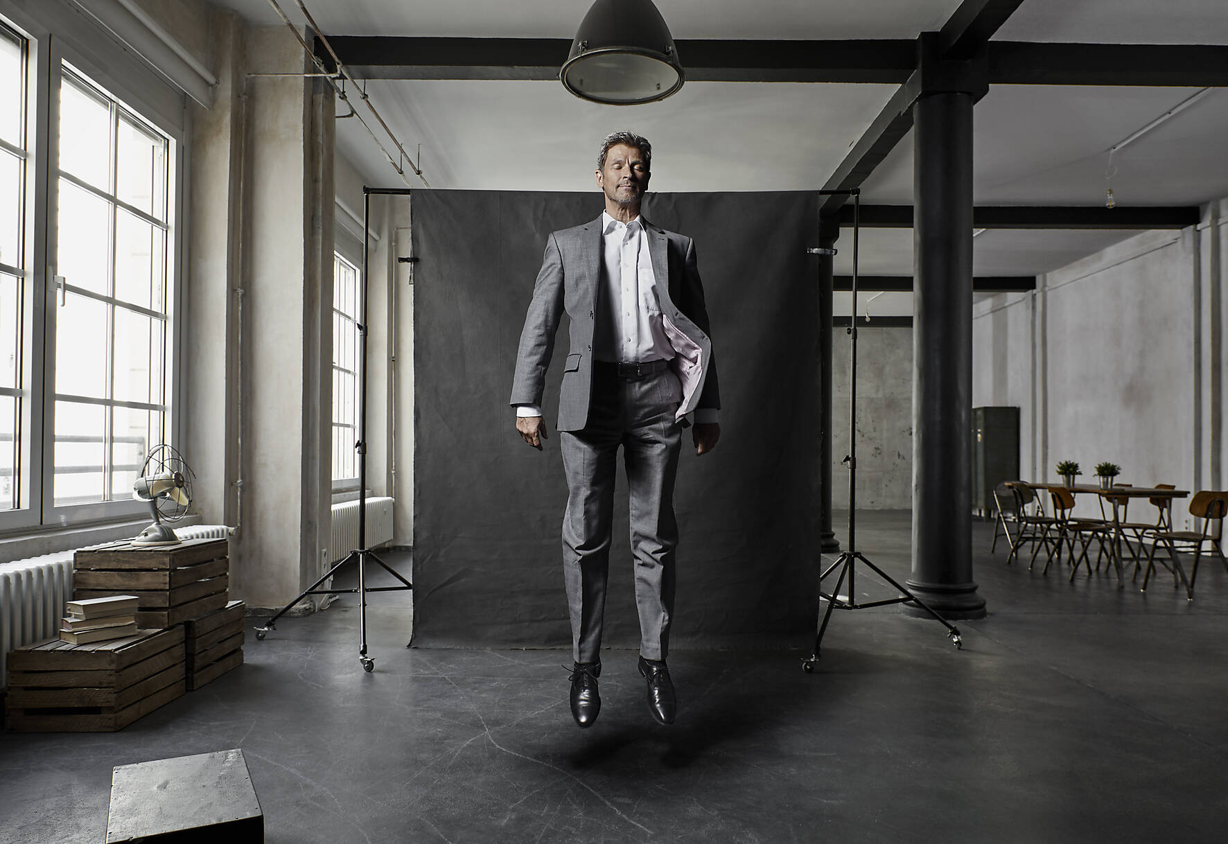 stock image, royalty-free, Mature businessman floating in front of black backdrop in loft