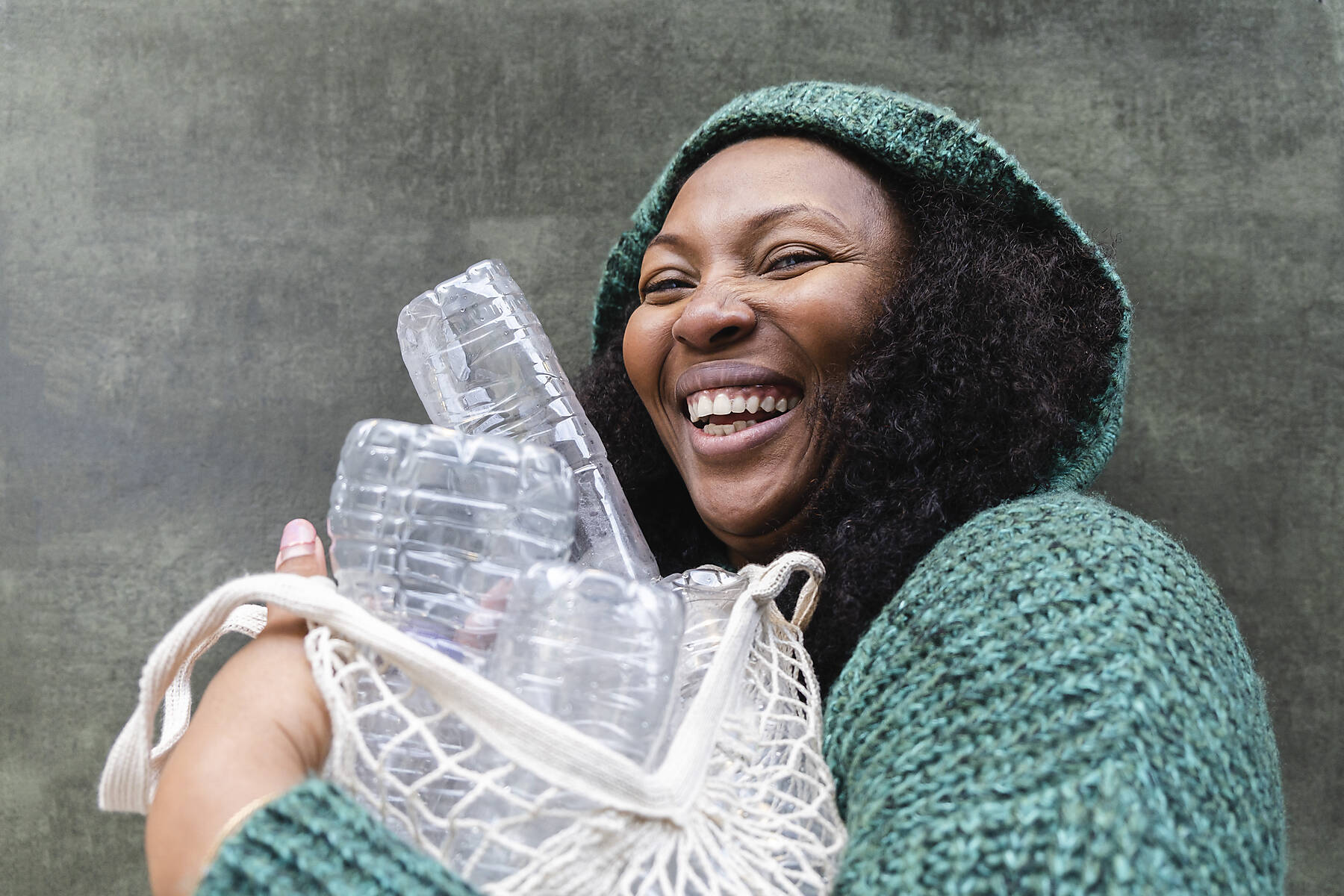 Stockfoto, lizenzfrei, Glückliche Frau hält Plastikwasserflaschen in einem Netzbeutel