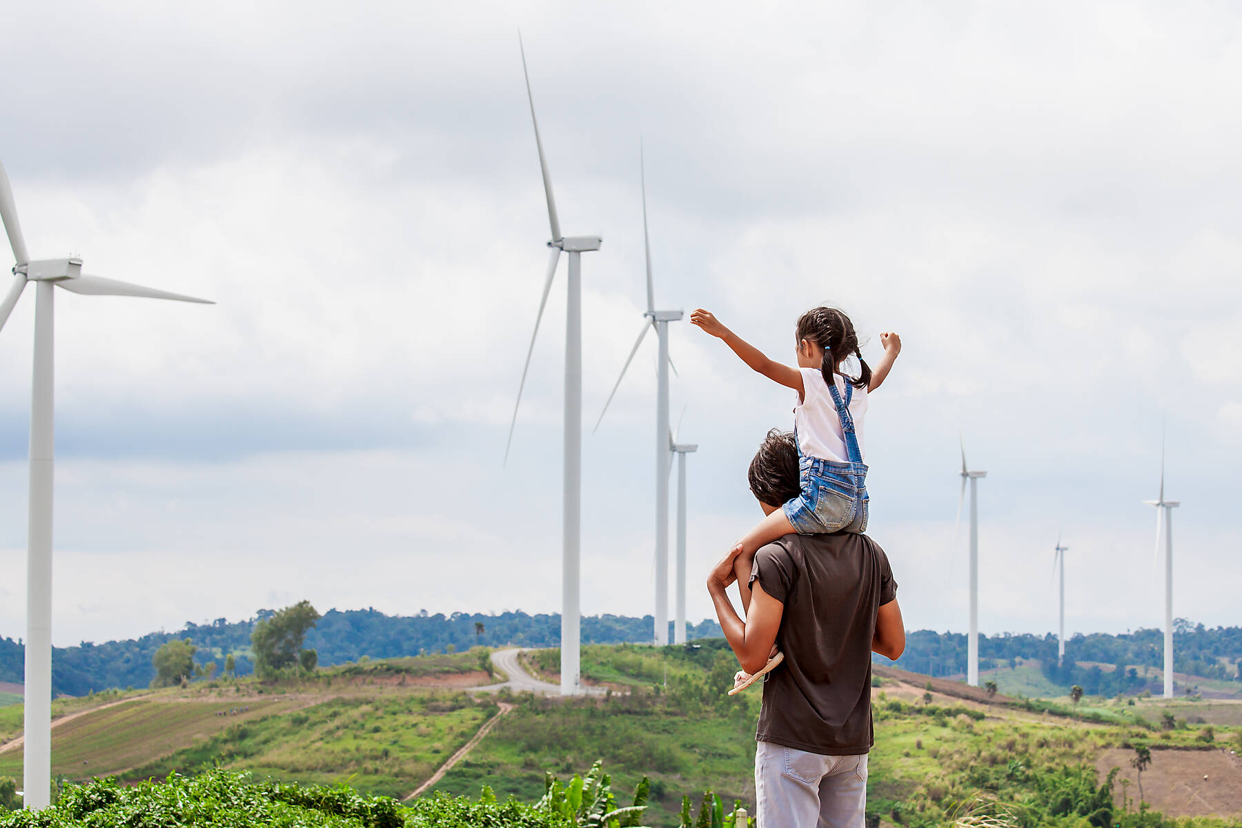 Stockfoto, lizenzfrei, Rückansicht der Tochter, die auf den Schultern des Vaters sitzt, mit Windmühlen im Hintergrund