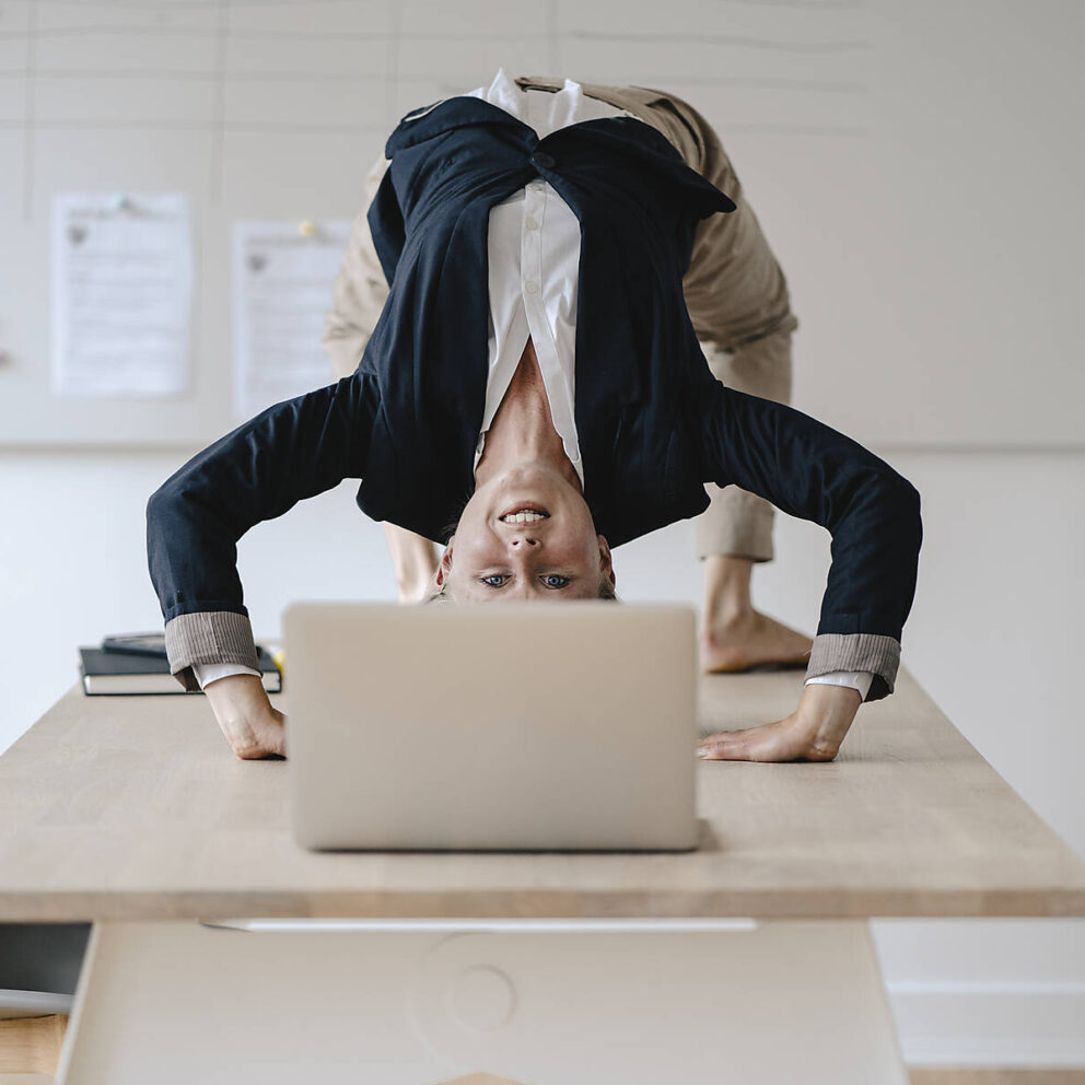 stockfoto, lizenzfrei, Junge Geschäftsfrau praktiziert Yoga auf dem Schreibtisch im Büro