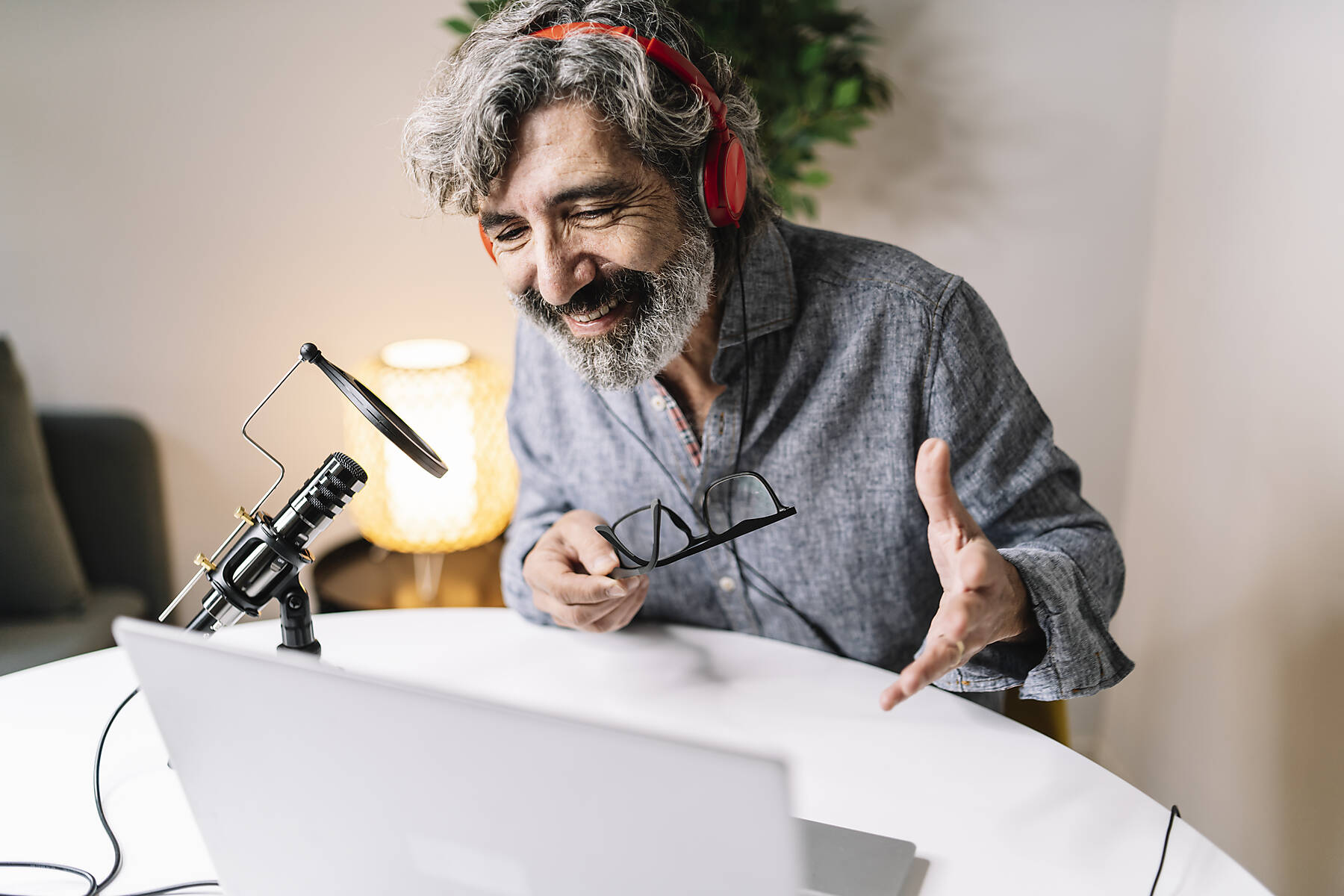 stock image, royalty-free, Senior male professional discussing while podcasting over laptop at office