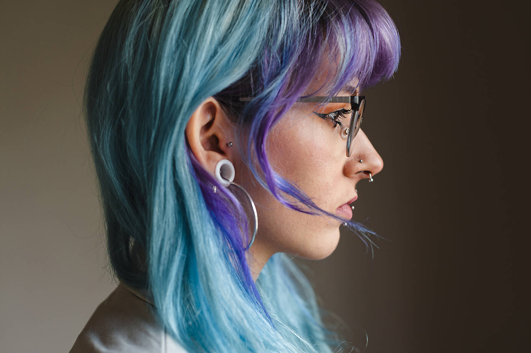Stockfoto, lizenzfrei, Nahaufnahme einer nachdenklichen jungen Frau mit gefärbten Haaren und Piercings an der Wand in einem alten Büro