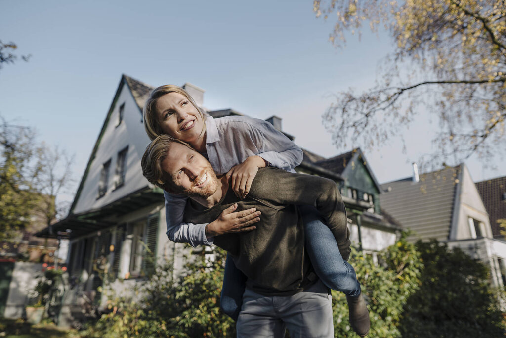 Stockfoto, lizenzfrei, Mann trägt seine Frau huckepack im Garten