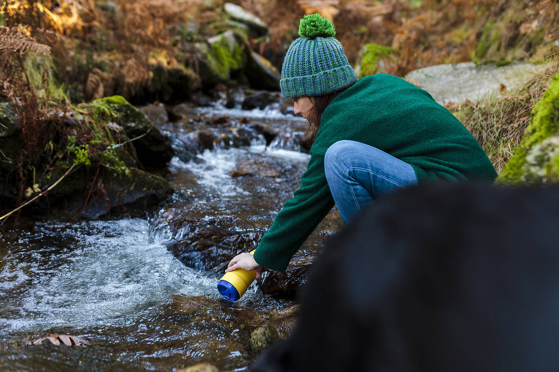 stock image, royalty-free, Woman filling bottle in stream at autumn forest