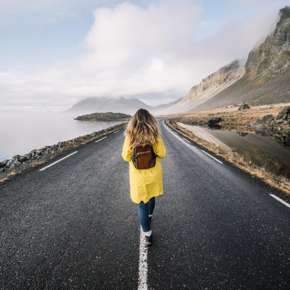 stockfoto, lizenzfrei, Island, Rückenansicht einer Frau mit Rucksack, die auf dem Mittelstreifen einer Landstraße geht