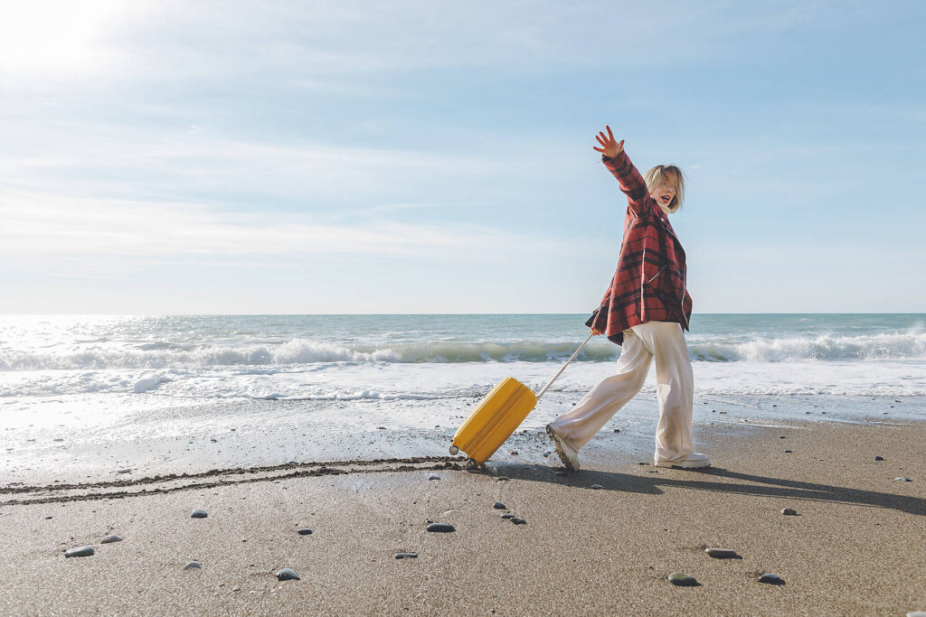 stock image, royalty-free, Cheerful woman with suitcase walking on seashore