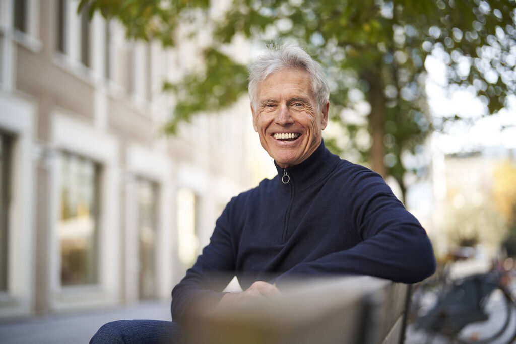 Stockfoto, lizenzfrei, Fröhlicher älterer Mann auf einer Bank sitzend