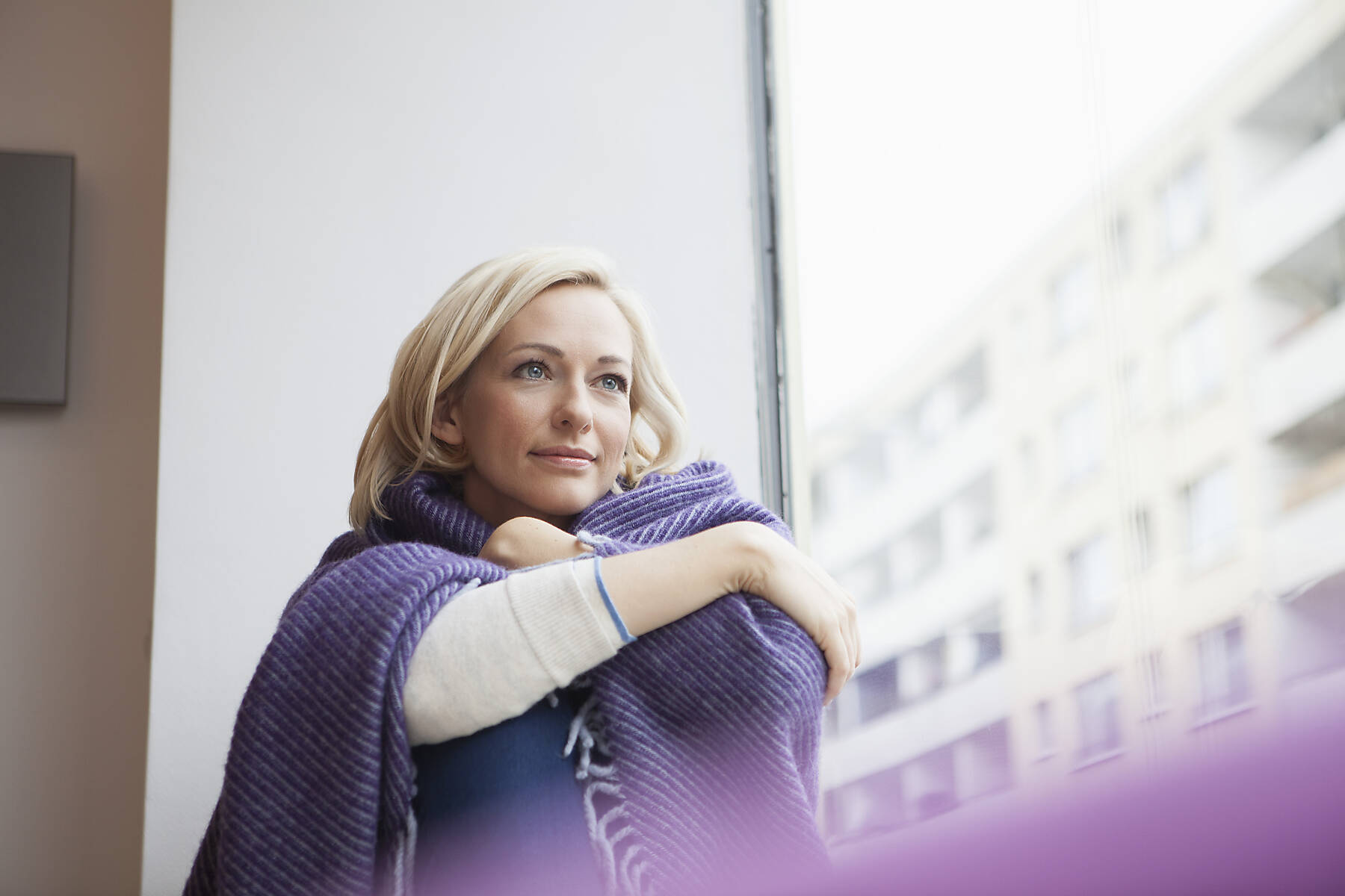 Stockfoto, lizenzfrei, Bildnis einer Frau mit Wolldecke beim Blick durchs Fenster