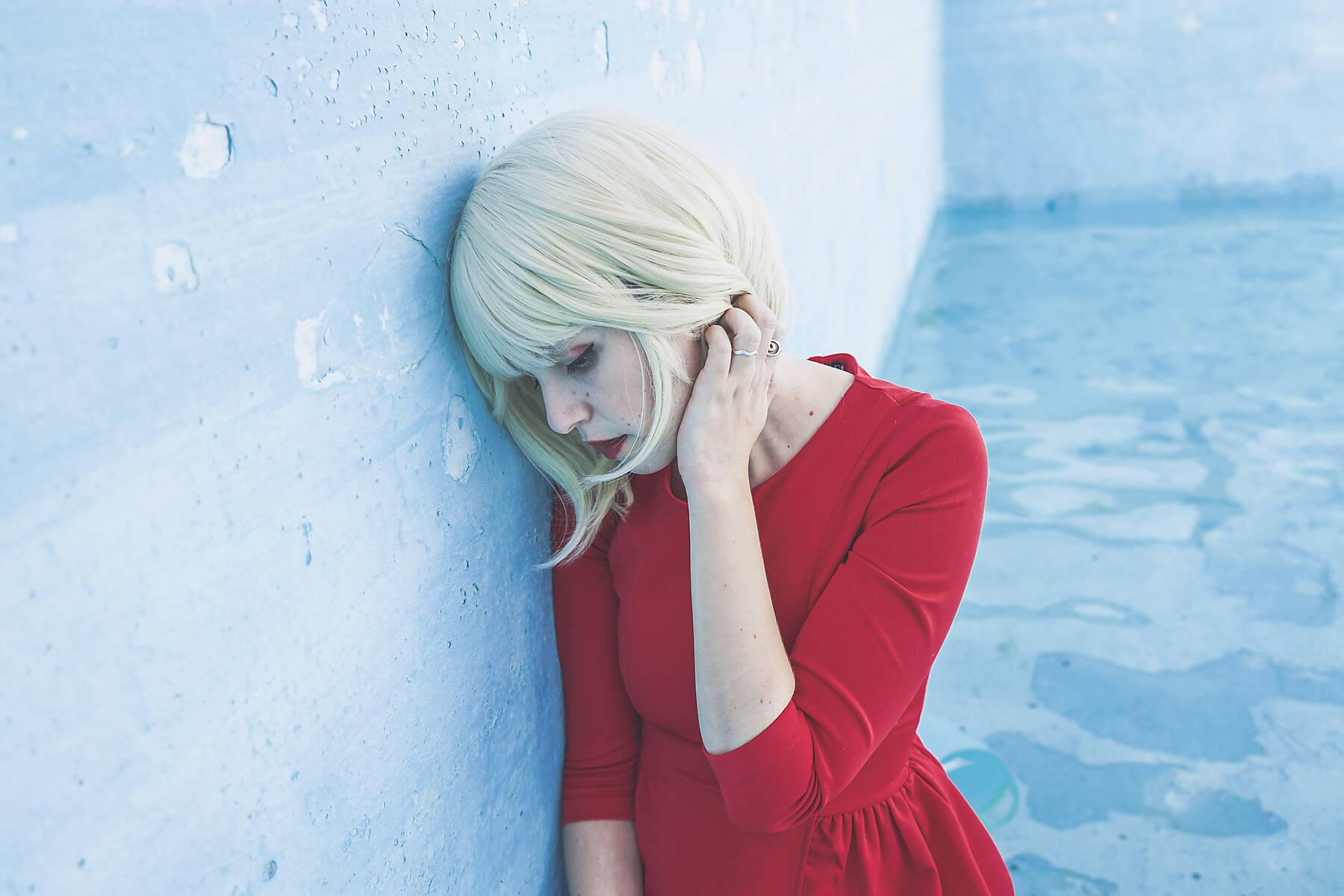 stock image, royalty-free, Sad woman with hand in hair leaning on wall at swimming pool