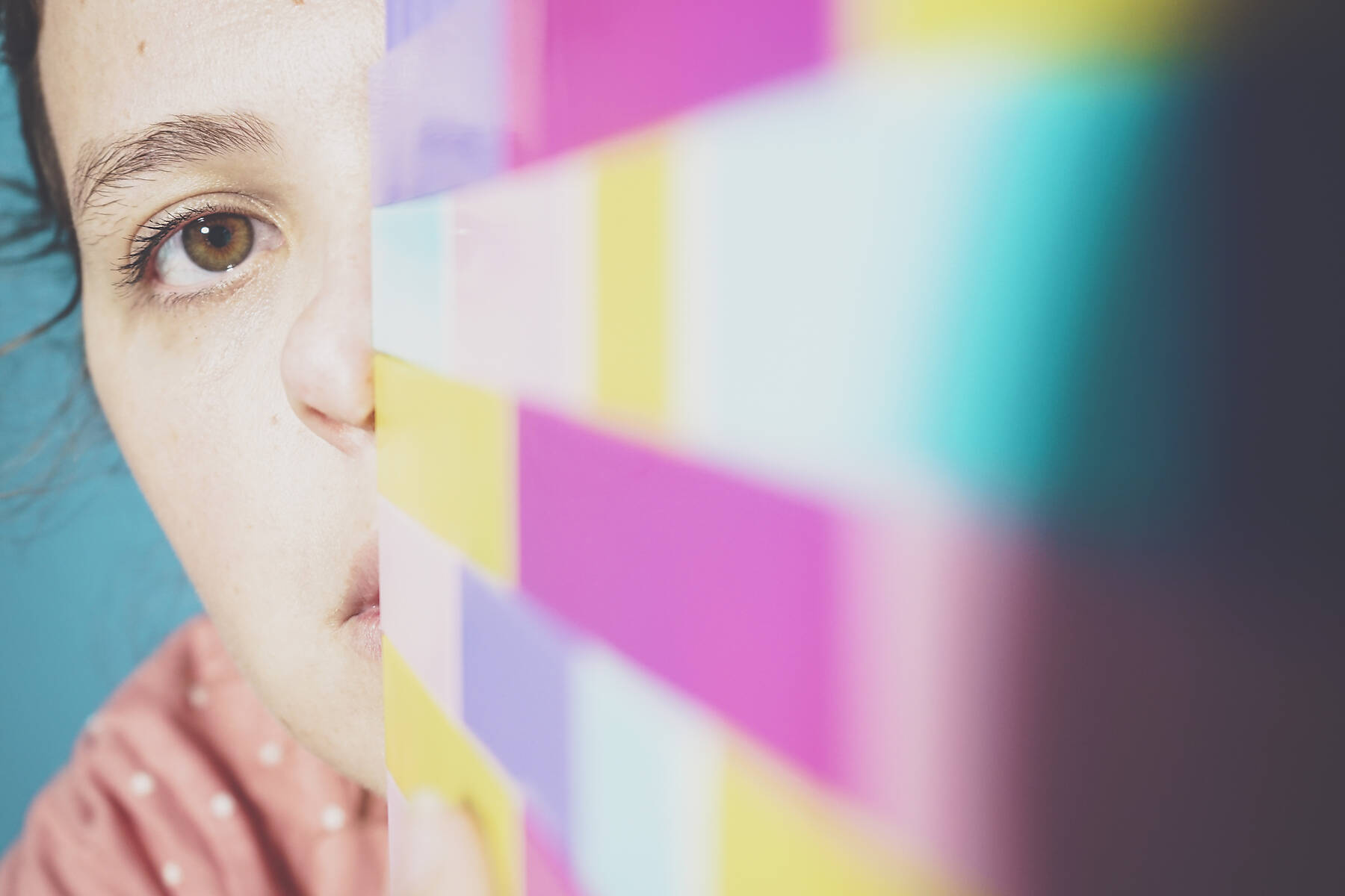 stock image, royalty-free, Face of adult woman peeking at camera from behind toy blocks