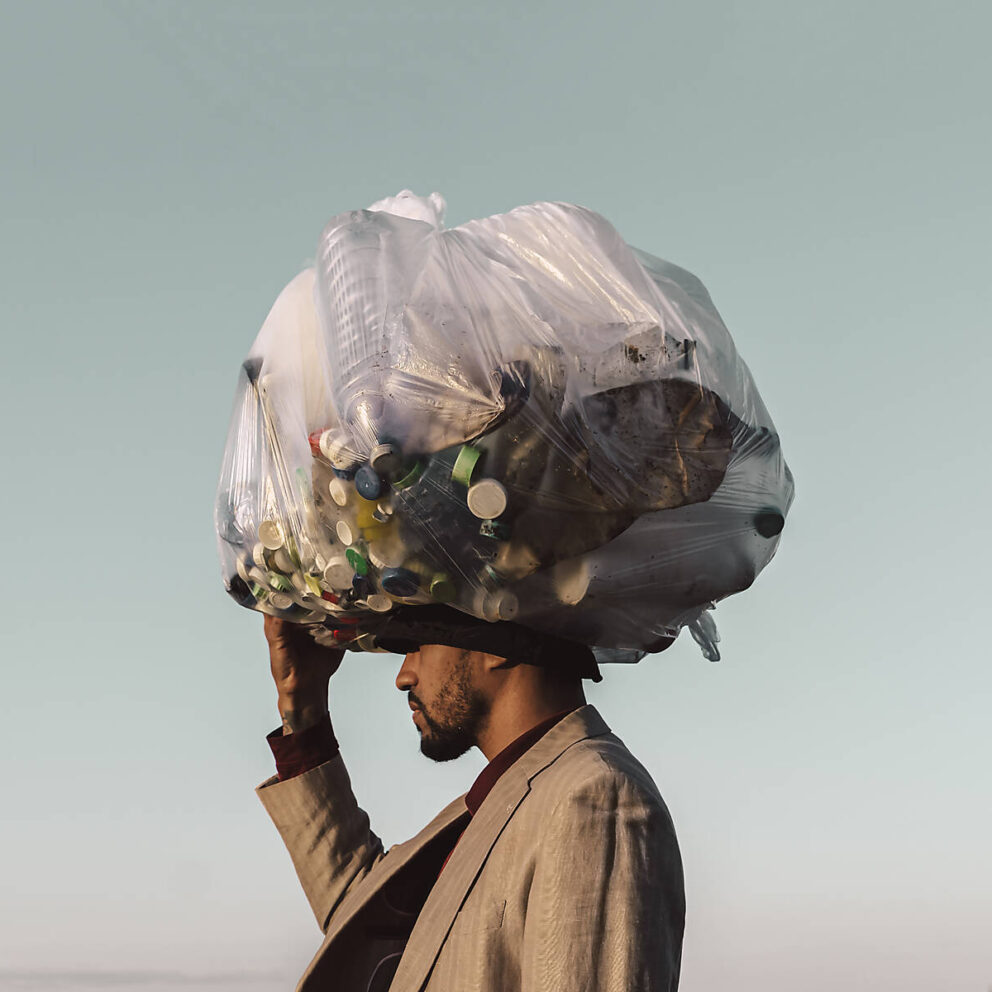 stock image, royalty-free, Young man carrying bag with plastic bottles under blue sky
