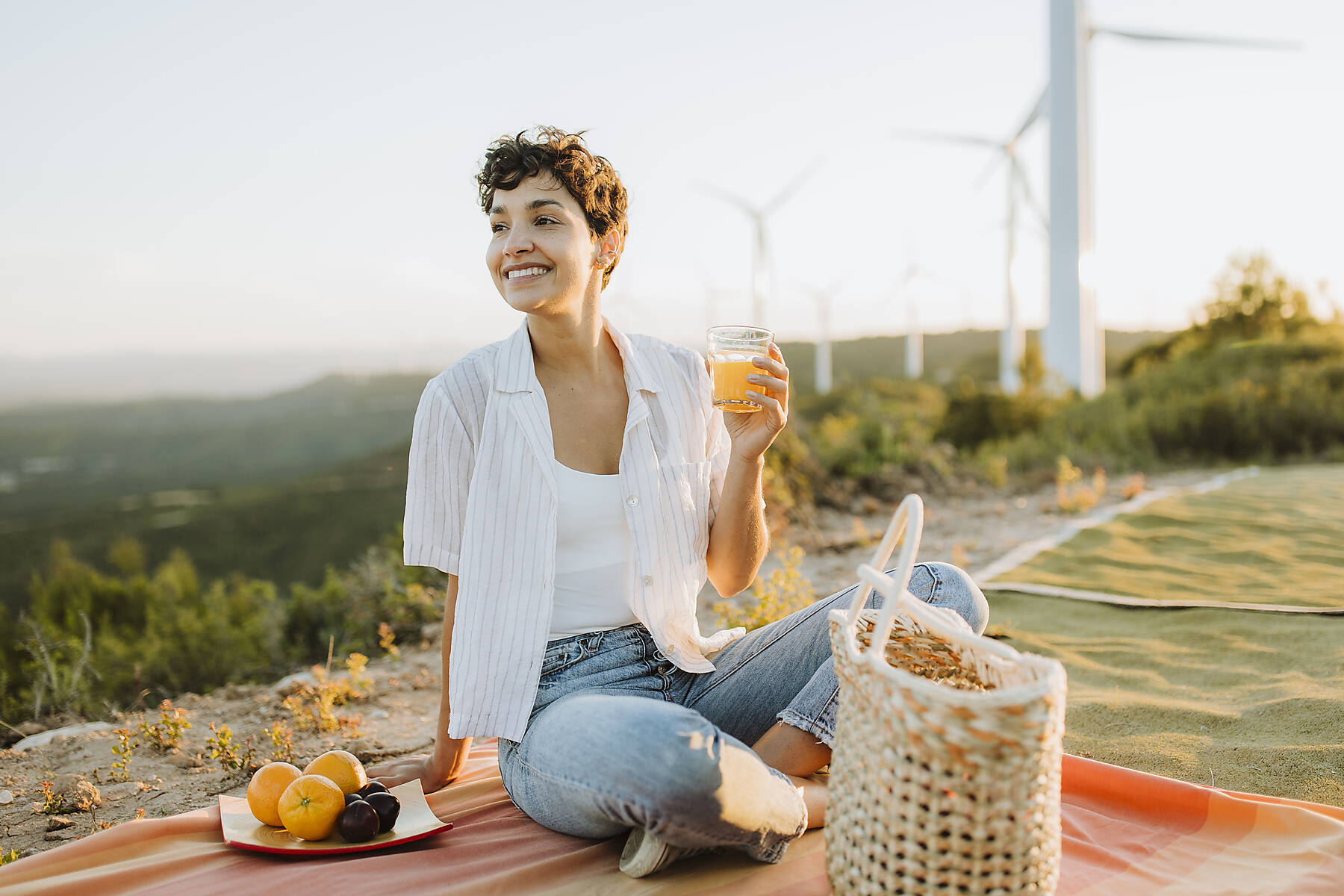 stock image, royalty-free, Smiling woman with juice glass sitting on mountain during picnic