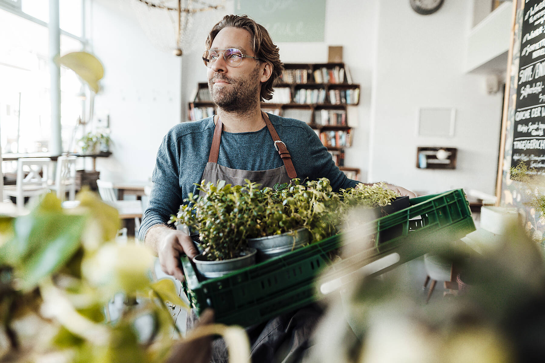 stock image, royalty-free, Thoughtful male owner with plant crate standing at coffee shop