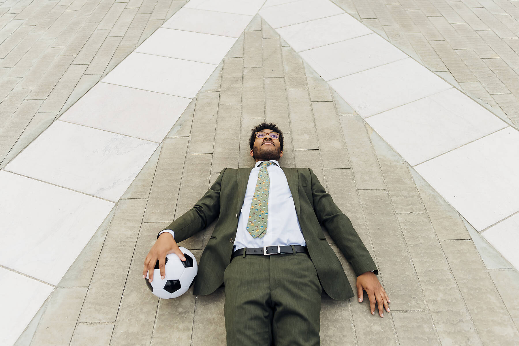 stock image, royalty-free, Businessman with soccer ball lying on footpath
