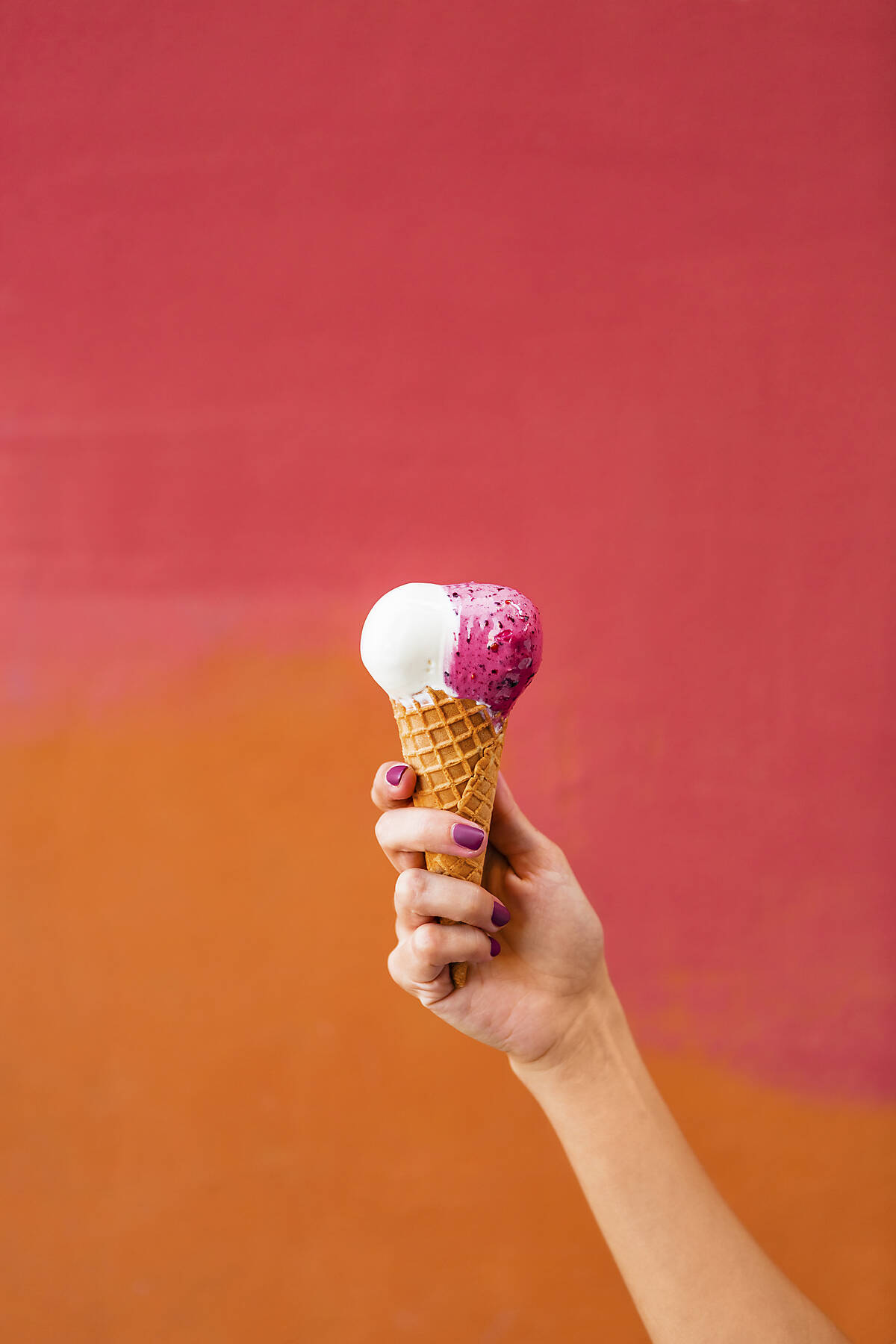 stock image, royalty-free, Woman's hand holding ice cream in front of colourful backgound