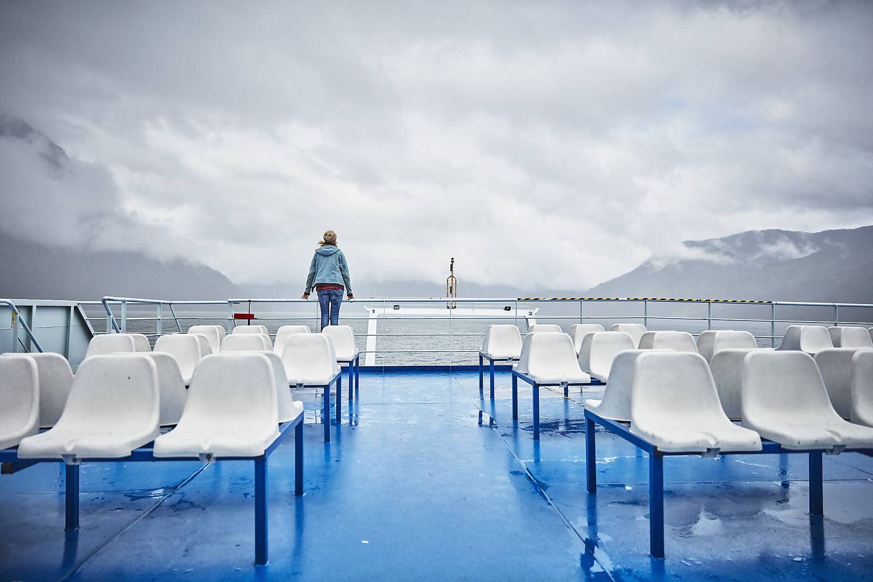 stockfoto, lizenzfrei, Chile, Hornopiren, Frau sitzt auf Reling einer Fähre und schaut auf Fjord