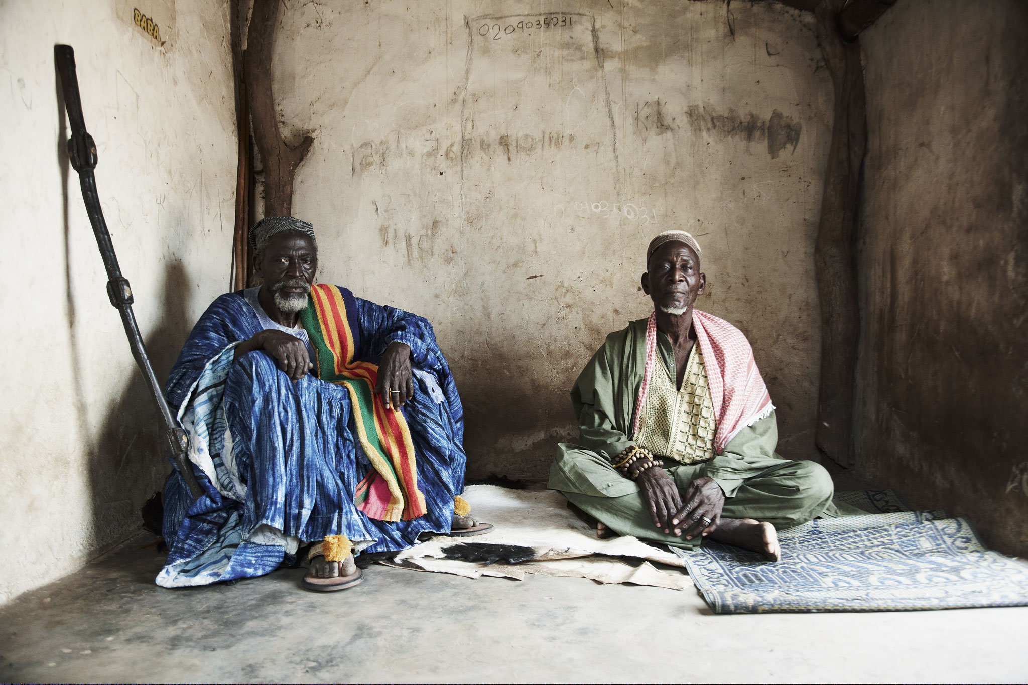 Iman und Dorfältester sitzen im Zelt auf dem Boden, Ghana