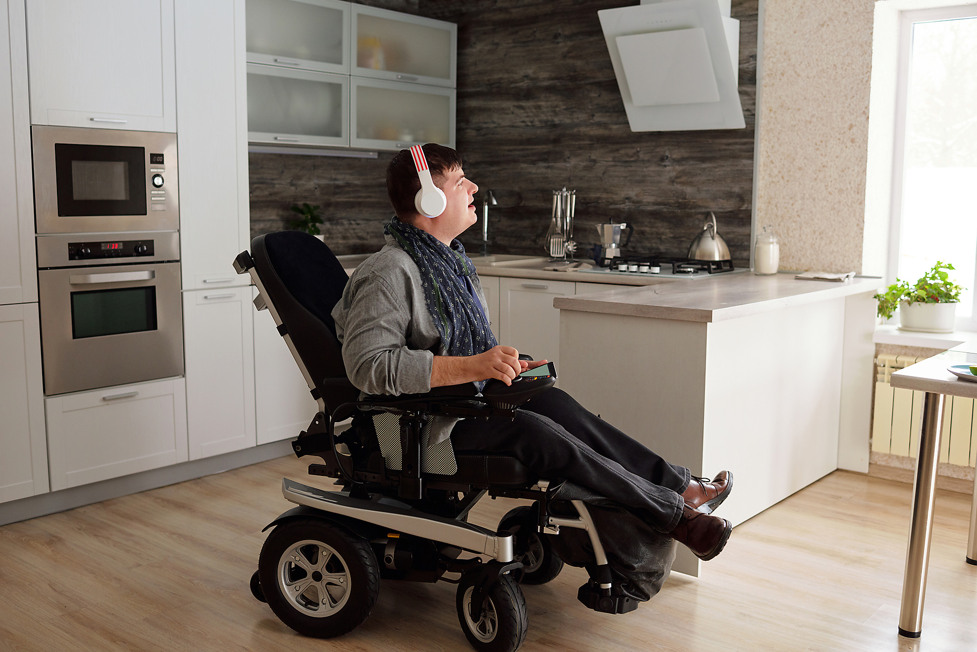 Stockfoto, lizenzfrei, Mann mit Behinderung im Rollstuhl hört zuhause Musik