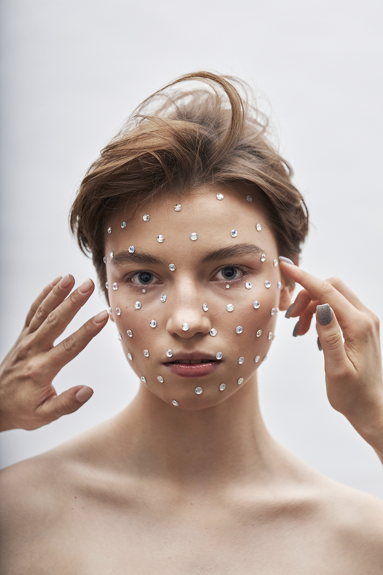 Stockfoto, lizenzfrei, Frauen kleben Strasssteine auf das Gesicht eines Teenagers vor weißem Hintergrund